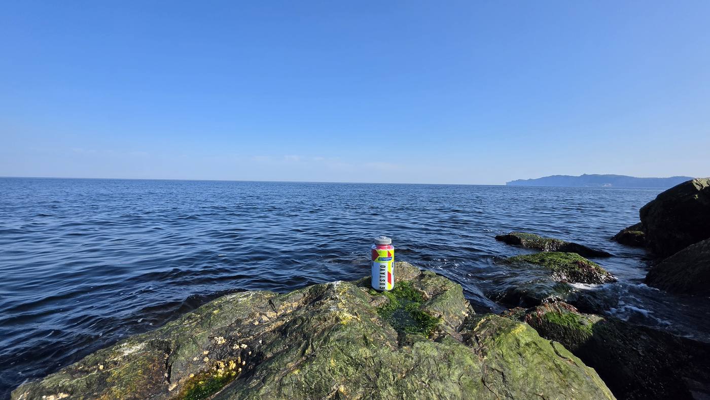 La bouteille sur un rocher au bord de l'eau, le cap à l'horizon