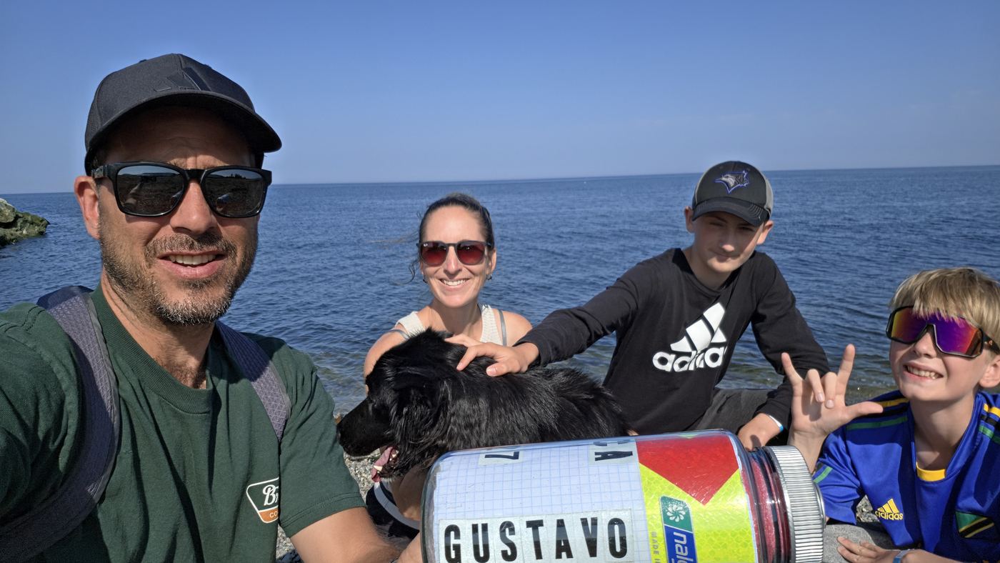 Quatre personnes et un chien sur la grève, la bouteille au premier plan